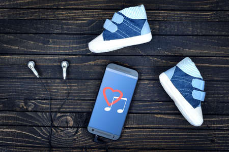 Love music on phone screen and earphones on wooden tableの写真素材