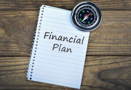 Financial Plan text and metallic compass on wooden tableの写真素材