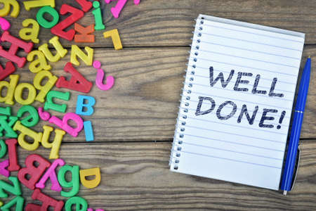 Well Done text on notepad and magnetic letters on wooden tableの写真素材