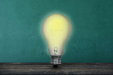 Green board and light bulb on tableの写真素材