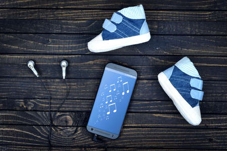 Music on phone screen and earphones on wooden tableの写真素材