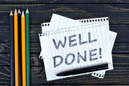 Well Done text on notepad and office tools on wooden tableの写真素材