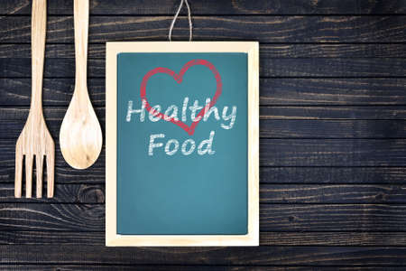 Love healthy food text on green board with fork and spoon on wooden tableの写真素材
