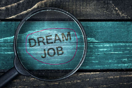 Dream Job text painted and magnifying glass on wooden tableの写真素材