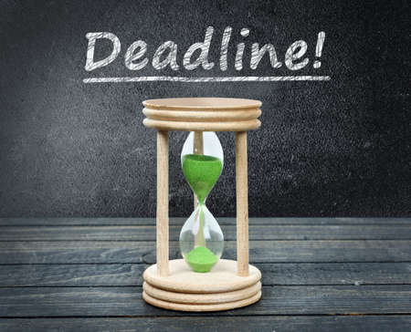 Deadline text and hourglass close-up on wooden tableの写真素材