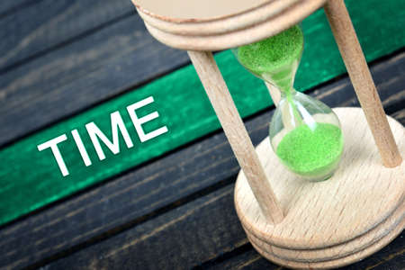Time text and hourglass on wooden tableの写真素材