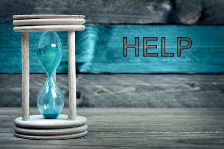 Help text and hourglass on table on wooden tableの写真素材