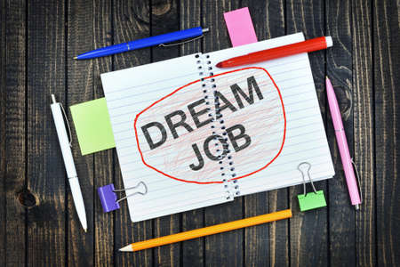 Dream Job text on notepad and office tools on wooden tableの写真素材