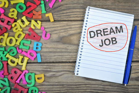 Dream Job text on notepad and magnetic letters on wooden tableの写真素材