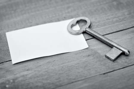 Closeup of key with empty note on wooden tableの写真素材