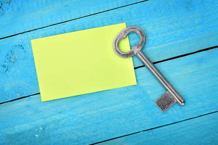 Closeup of key with empty note on wooden tableの写真素材
