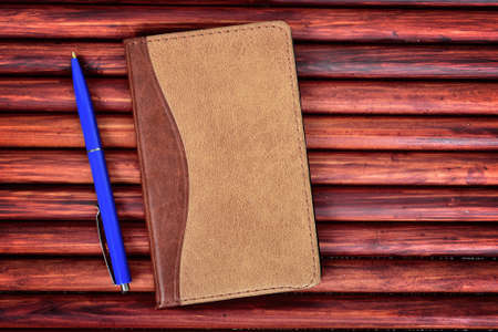 Notepad and pen on wooden tableの写真素材