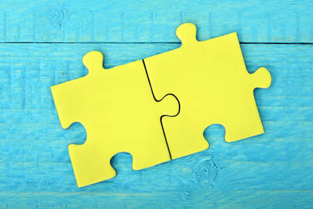 Two puzzle pieces on wooden tableの写真素材
