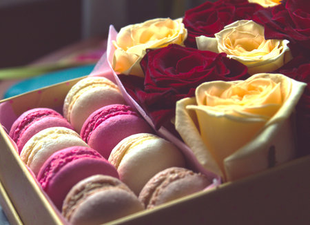 Macaroon and box with flowers, red and yellow roses backgroundの写真素材