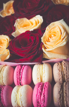 Macaroon and box with flowers, red and yellow roses backgroundの写真素材