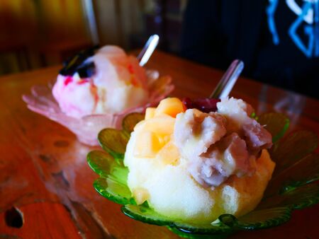 Shaved ice with melon and taro on top in green cup from small cafe in Thailandの写真素材