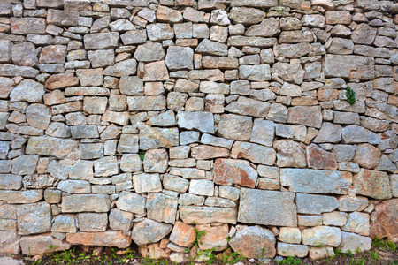 An old wall in Puglia. Italian masonry fence. Ancient stone with green grass. Background. Attrition. Gray, orange, blue, purple.の写真素材