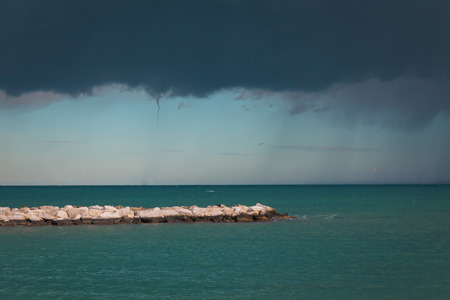 The storm on the sea begins. Dark blue clouds with rain. Before the start of a tornado. The calm sea is azure before the hurricane.の写真素材