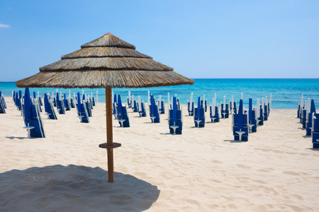 Straw umbrella with background blue sea, sky and sand beach. Nobody, outdoor. Italy, Pugliaの写真素材