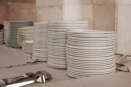 A lot of white ceramic plates and cutlery on the table in restaurant in Italyの写真素材