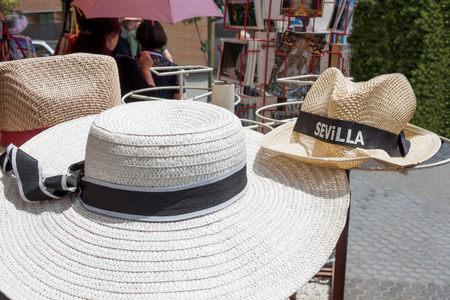 A straw woman's hat with ribbon and a straw man's hat with the inscription Sevilla. Summer goods for tourists in Spain in a tourist placeの写真素材