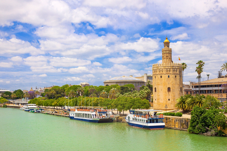 View from river Guadalquivir to Golden tower Torre del oro at sunny summer day, blue sky and white cloudsの写真素材