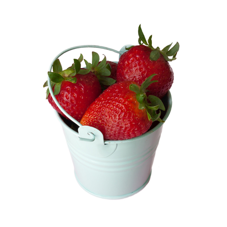Beautiful ripe red fresh strawberries with green leaves in green colored pail on white background, close-upの写真素材