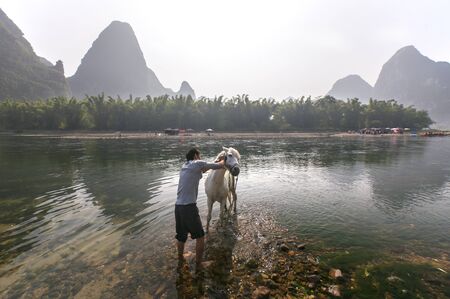 Man cleaning up for his pet horse in the lakeのeditorial素材