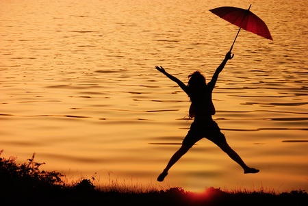 Umbrella woman jumping and sunset silhouette in Lake の写真素材