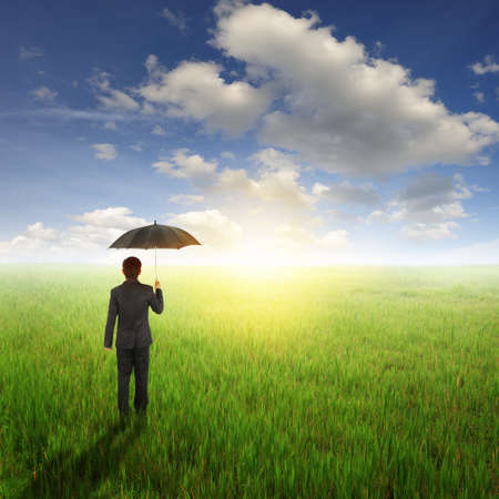 Business man Umbrella and standing to sun sky in grassland with umbrellaの写真素材