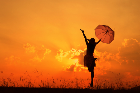 Umbrella woman jumping and sunset silhouetteの写真素材