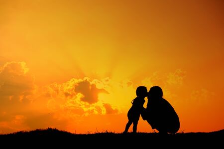 silhouette of Son is kissing his mother outdoors at sunsetの写真素材
