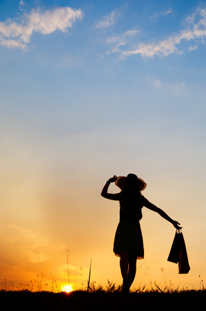 Relax Woman holding shopping bags in sunset silhouetteの写真素材
