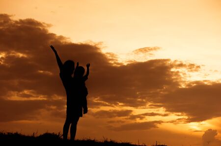 silhouette of a mother and son playing outdoors at sunset with copy spaceの写真素材