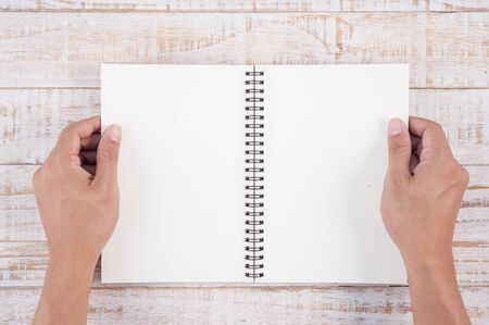 Man hand holding notebook on wood table for text and background.の写真素材