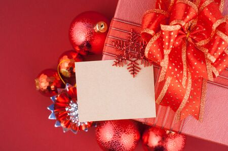Christmas gift box with decorations and card on red backgroundの写真素材