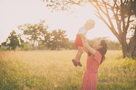 A mother and son playing in grass fields outdoors at evening.Vintage Tone and copy spaceの写真素材