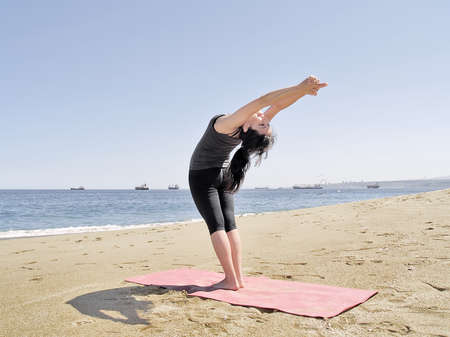 Yoga teacher practising at the beach pose arda chandrasanaの写真素材
