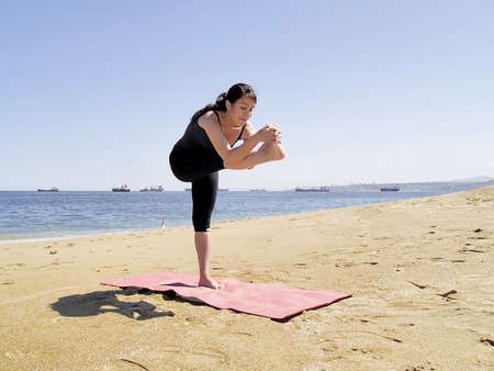 Yoga teacher practising at the beach pose dandayamana janushirasanaの写真素材