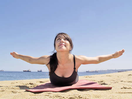 Yoga teacher practising at the beach pose paorna salabhasanaの写真素材
