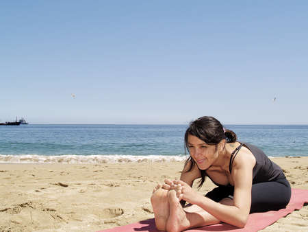 Yoga teacher practising at the beach pose sit-upの写真素材