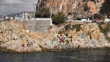 VALPARAISO,CHILE:FEBRUARY 11. Group of young people bathing at the coast on February 11, 2011 in Valparaiso, Chile. A long avenue from 2004 rounds the hill of Playa Ancha for some miles and many people fill the rocks to take a bath.のeditorial素材