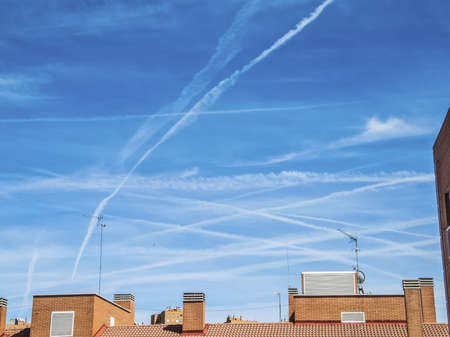 Chemtrails on blue sky over city buildingsの写真素材