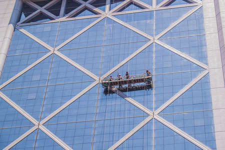 Santiago, February 2011. Professional workers clean the windows of an skyscraper from outside with a platform.のeditorial素材
