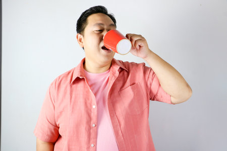 Man Enjoying a Drink from a red cupの写真素材