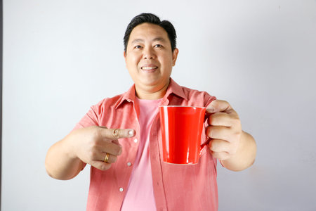 Man Holding a Red Mug and pointing finger into red mug