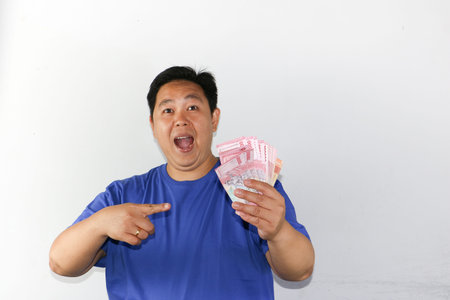 Asian man holding a lot of money in his hand. Isolated on white background.