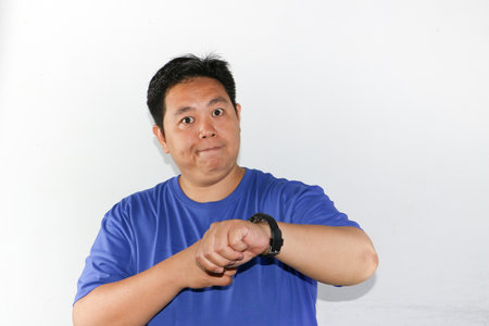 Asian man in blue t-shirt with watch on white backgroundの写真素材