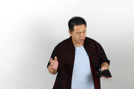 Curious expression asian guy looking at empty wallet