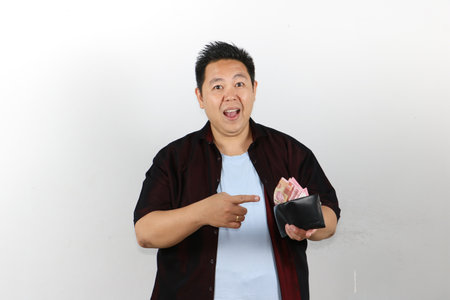Winning gesture young man holding wallet full of money, bank notesの写真素材